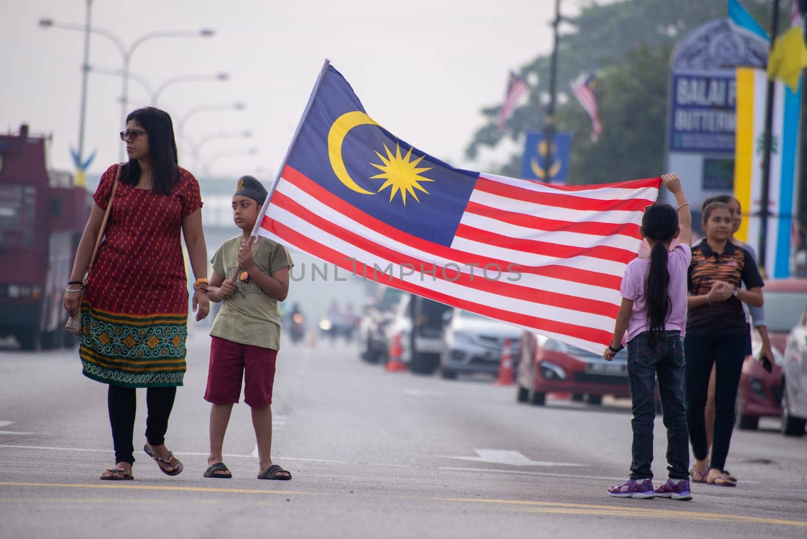Butterworth, Penang/Malaysia - Aug 31 2019: A Malaysian family hold the flag at street during Merdeka celebration.