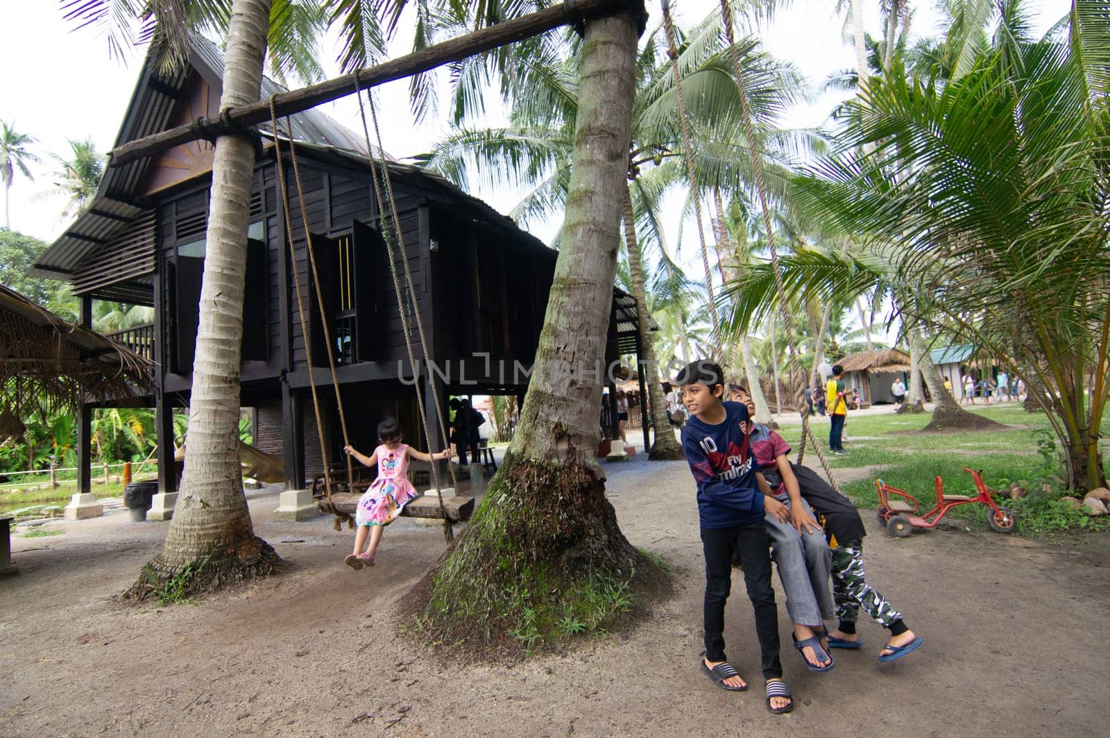 Penaga, Penang/Malaysia - Oct 27 2019: Kids have fun play swing in front Malays wooden house.