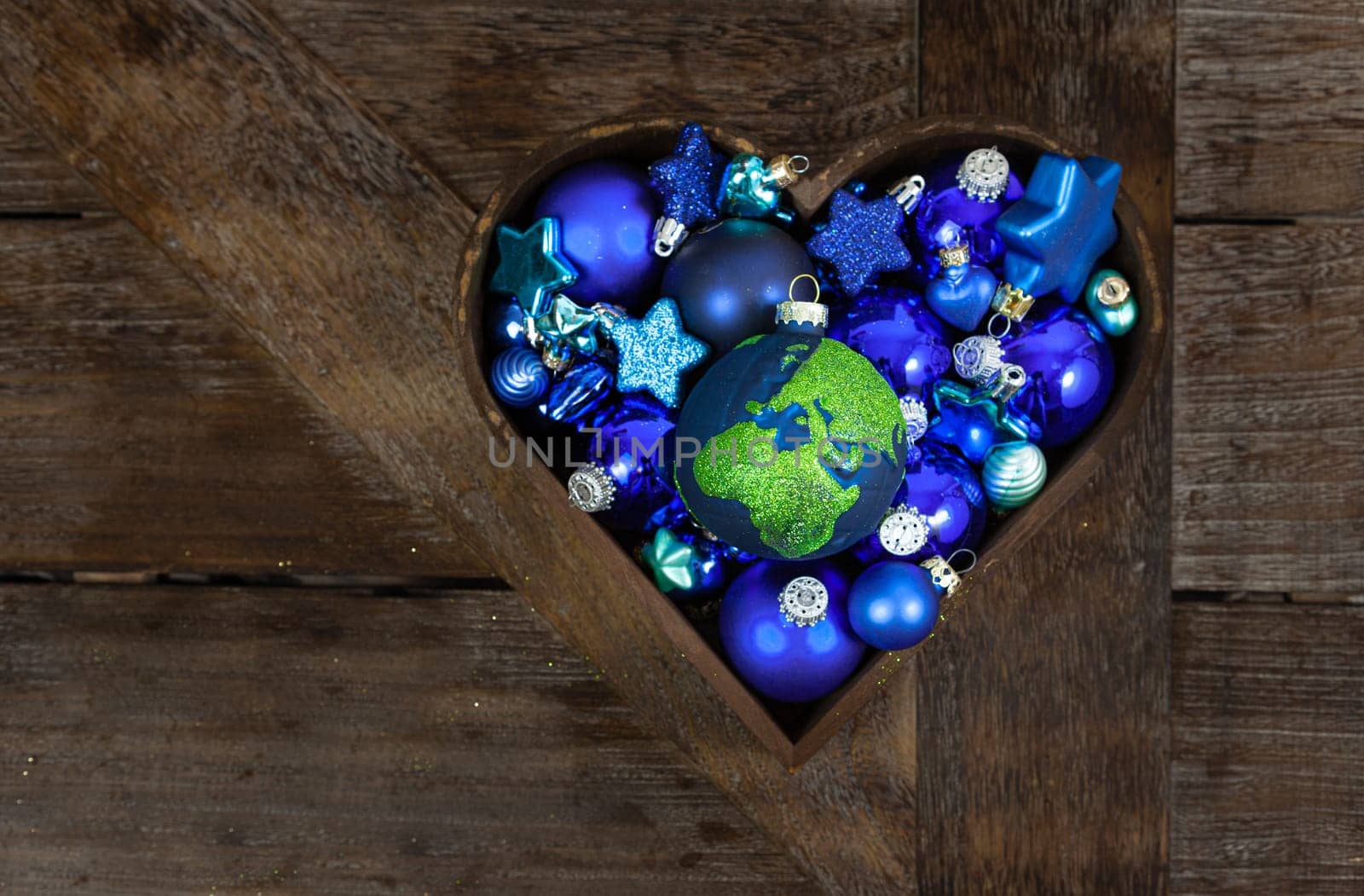 Blue Christmas baubles in a heart on wooden background
