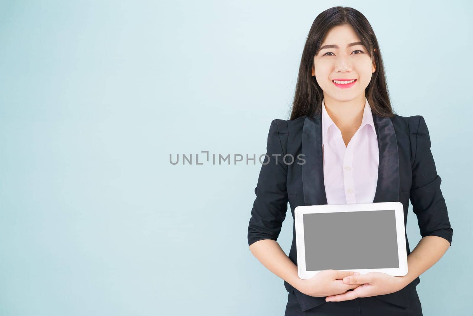 Young women in suit holding her digital tablet standing against blue background