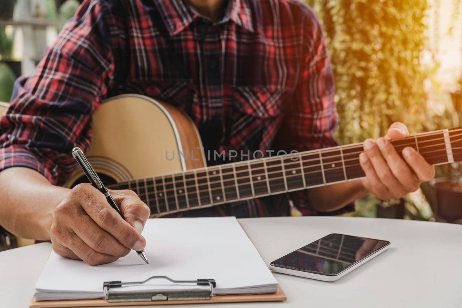 A Song writer holding pen for compose a song. Musician playing acoustic guitar. Live music and abstract musical concept.