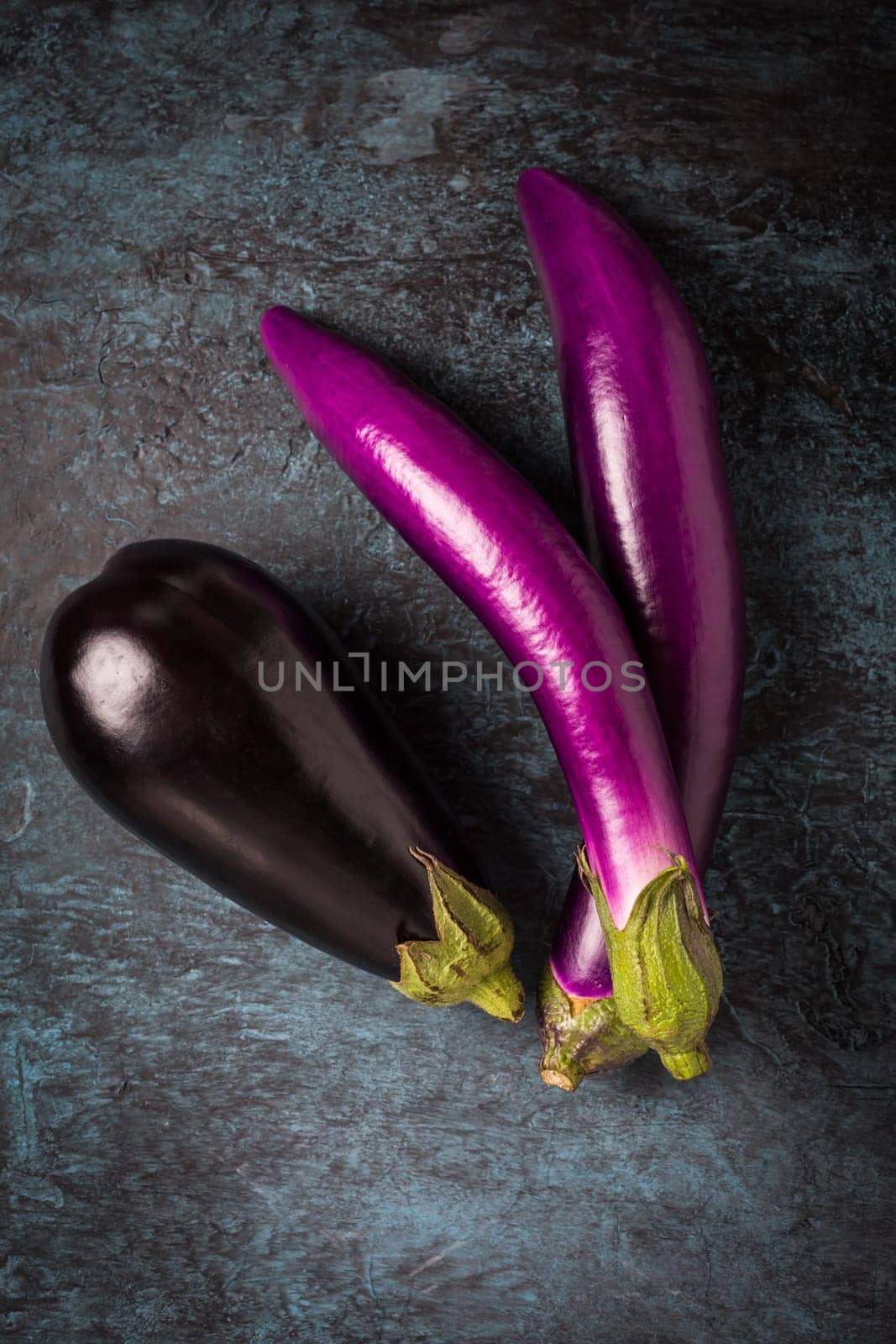 Assortment of fresh aubergines on dark background