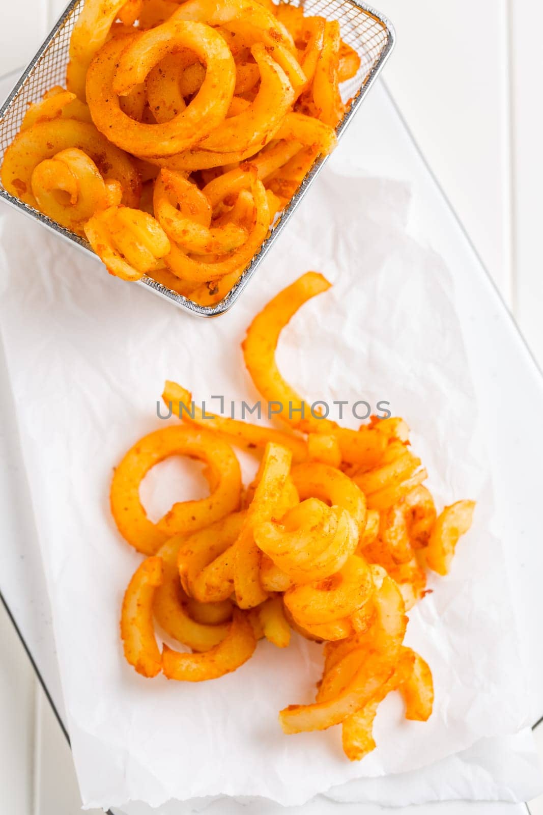 Spicy seasoned curly fries. Ready to eat on white background