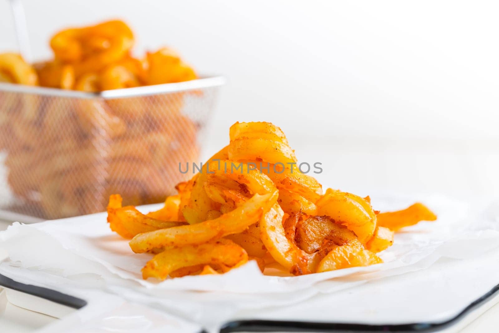 Spicy seasoned curly fries. Ready to eat on white background