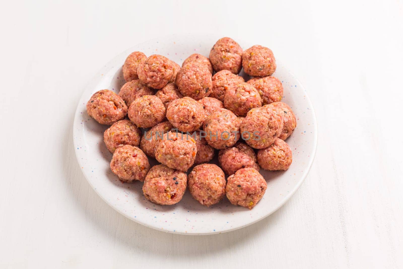 Raw meatballs on plate, ready for cooking or baking on white background