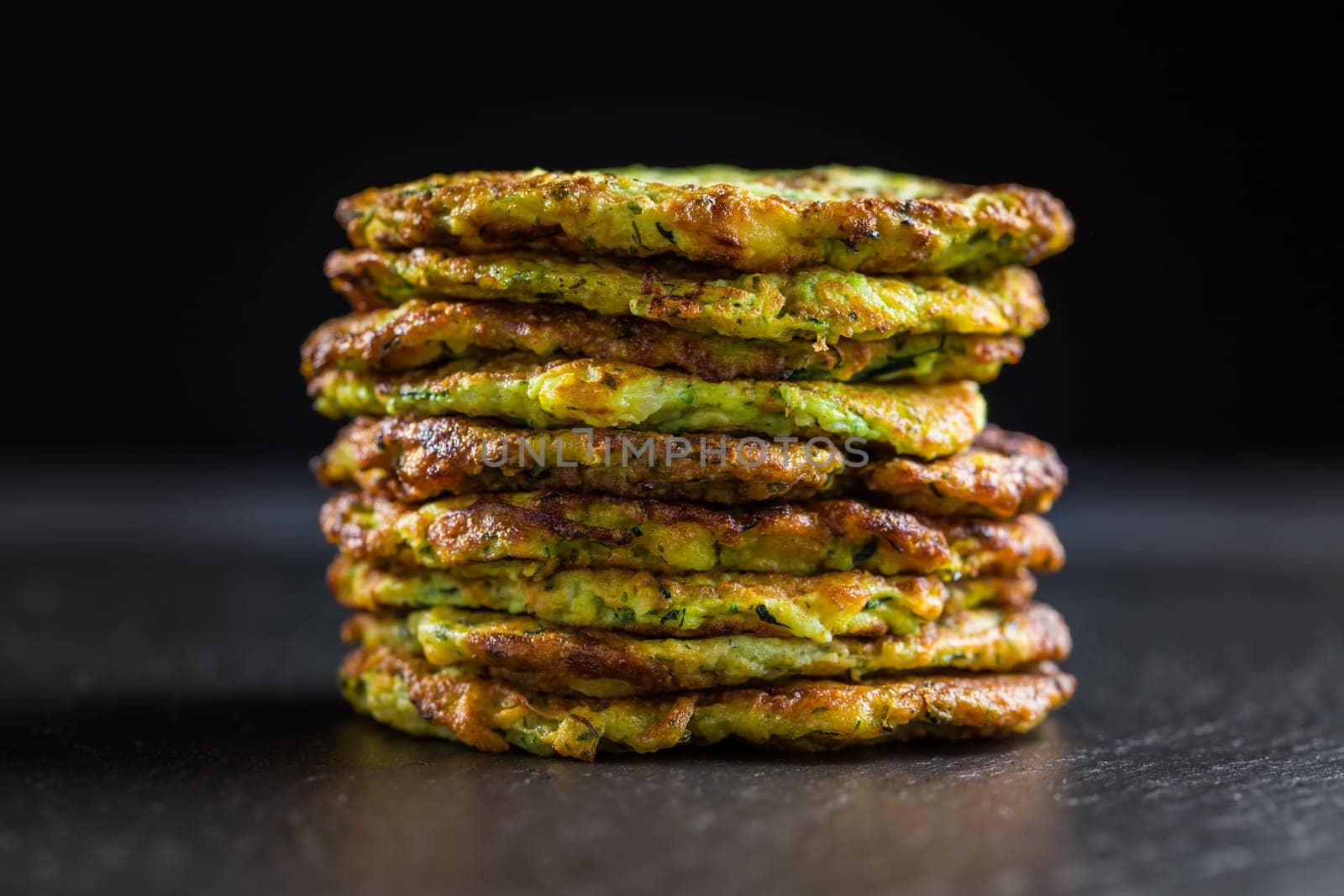Zucchini pancakes on black background