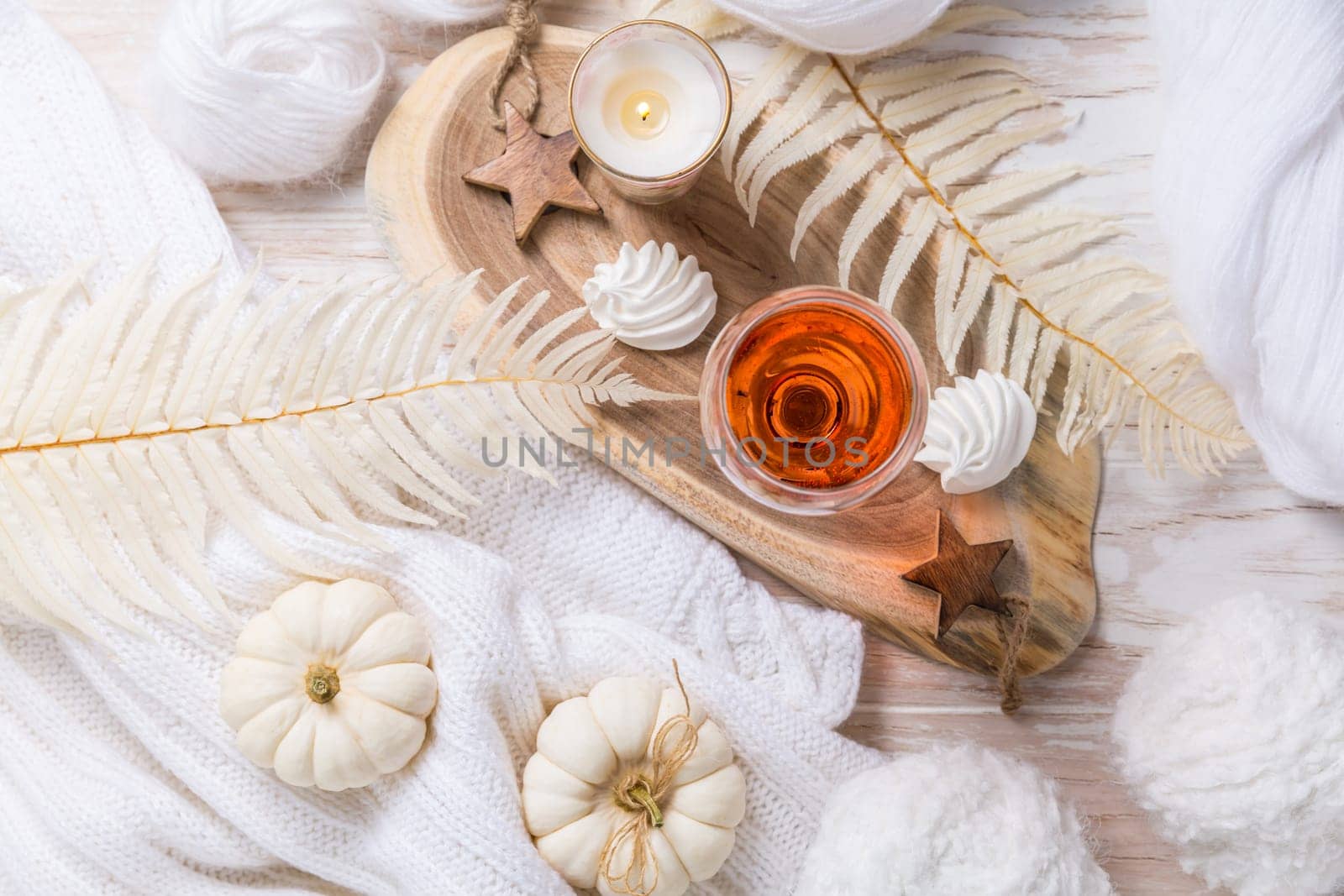 Cosy still life for winter and autumn with glass of pink wine, pumpkin cookie, wool and warm sweater