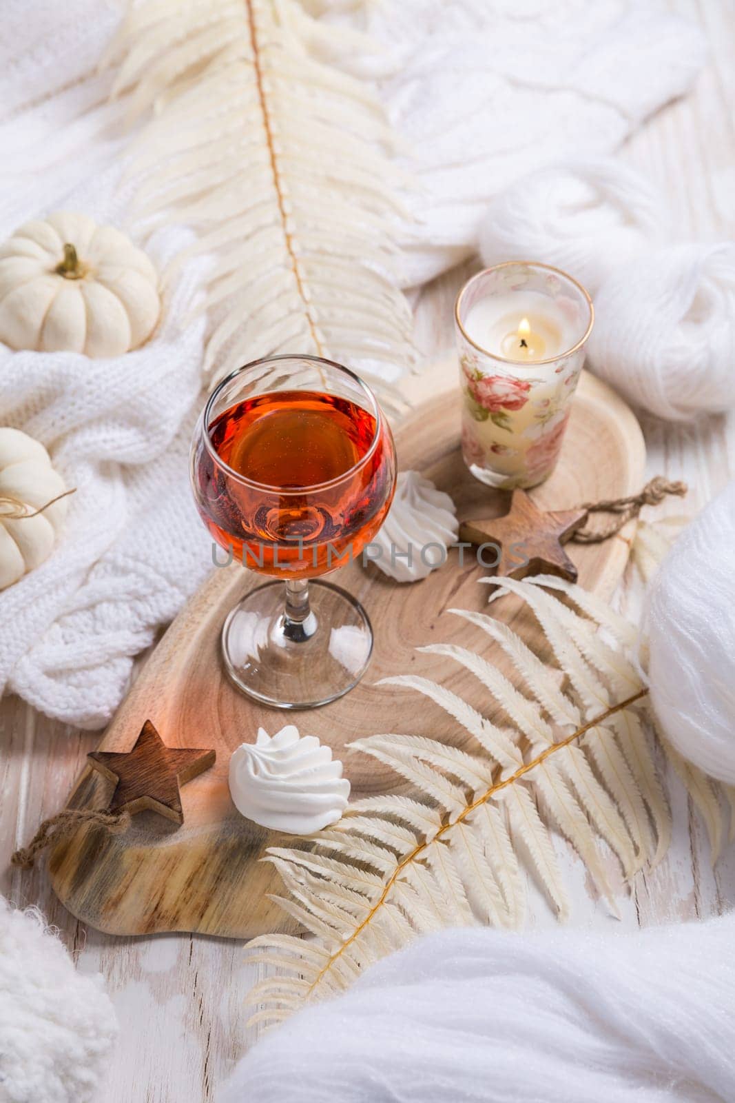 Cosy still life for winter and autumn with glass of pink wine, pumpkin cookie, wool and warm sweater
