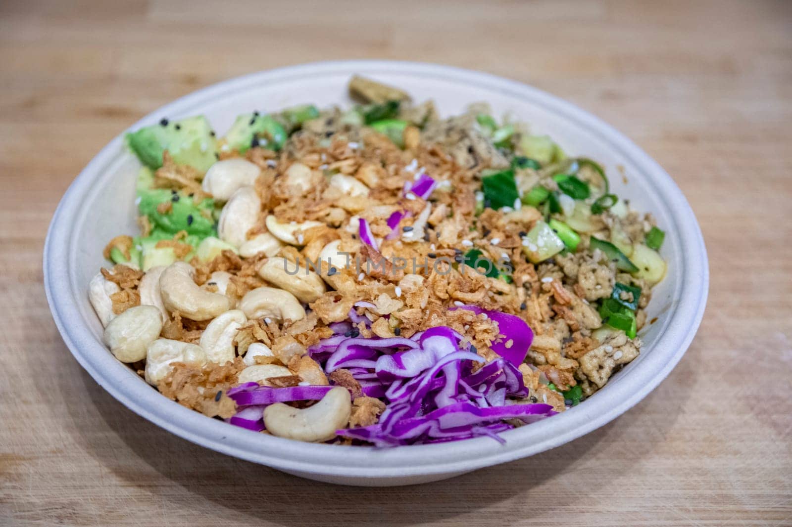 Vegan poke bowl with cashew nuts, red cabbage, dried onions, avocado and much more ingredients. Healty food. Ready to eat.
