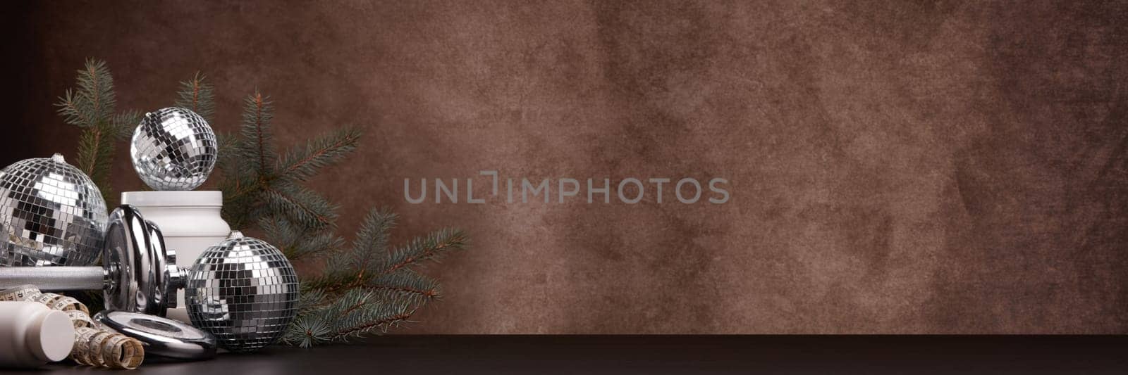 Sports nutrition (supplements), sports equipment, branch of fir,  Christmas ornaments on dark brown background with copy space. Fitness, sport or healthy lifestyle concept. New Year and Christmas.