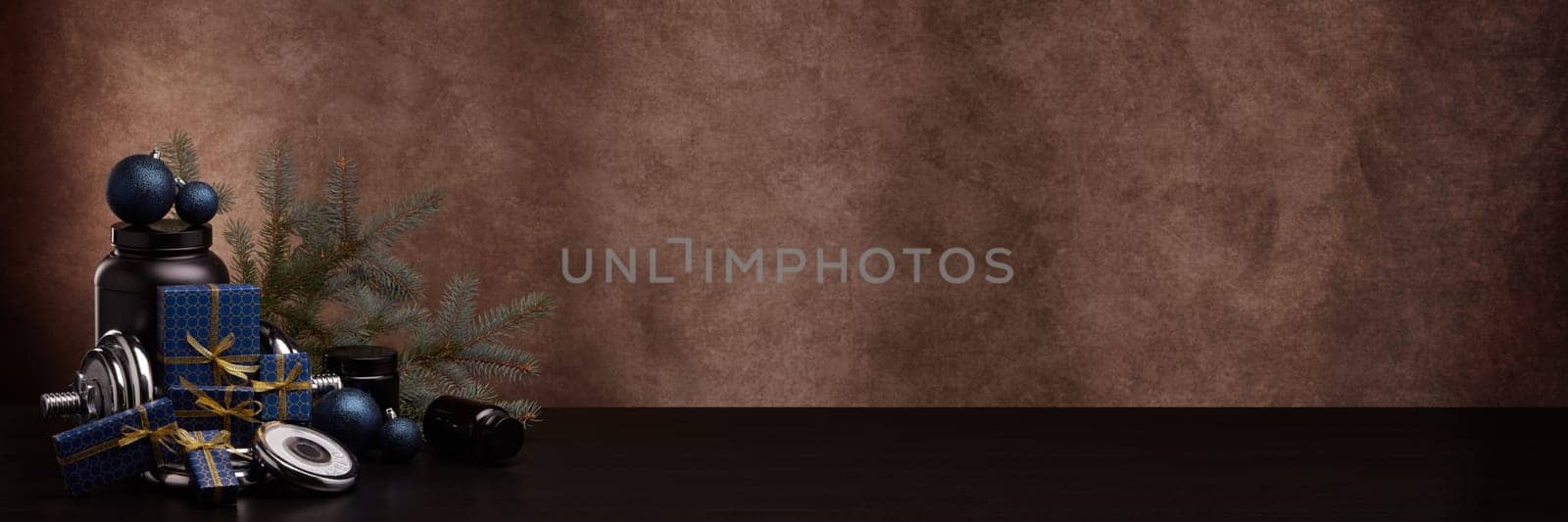 Sports nutrition (supplements), sports equipment, fir branch,  gift boxes, Christmas ornaments on dark brown background with copy space. Fitness, sport, healthy lifestyle concept. New Year. Christmas.