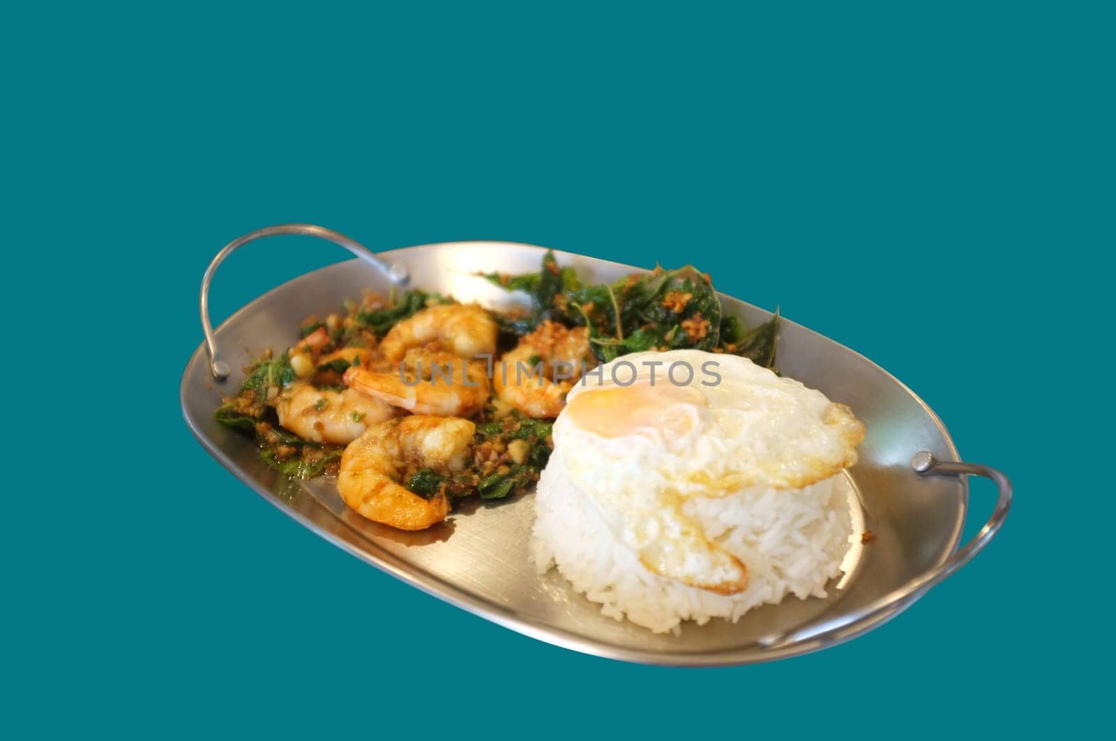 Stirred-fry shrimps or prawns with basil leaves, fried egg over rice on blue background . Thai food