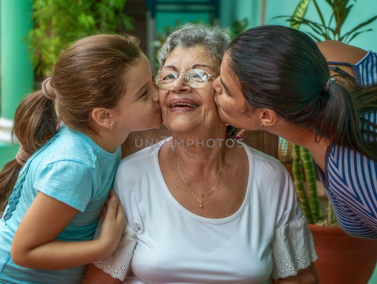 A girl and a young woman kissing an old woman