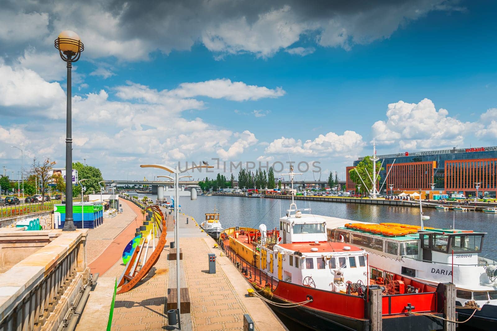 Boats docked on Wieleckie Quay, view from Long Bridge, called Most Dlugi in Szczecin, Poland. Promenade and boulevards on Odra River embarkment
