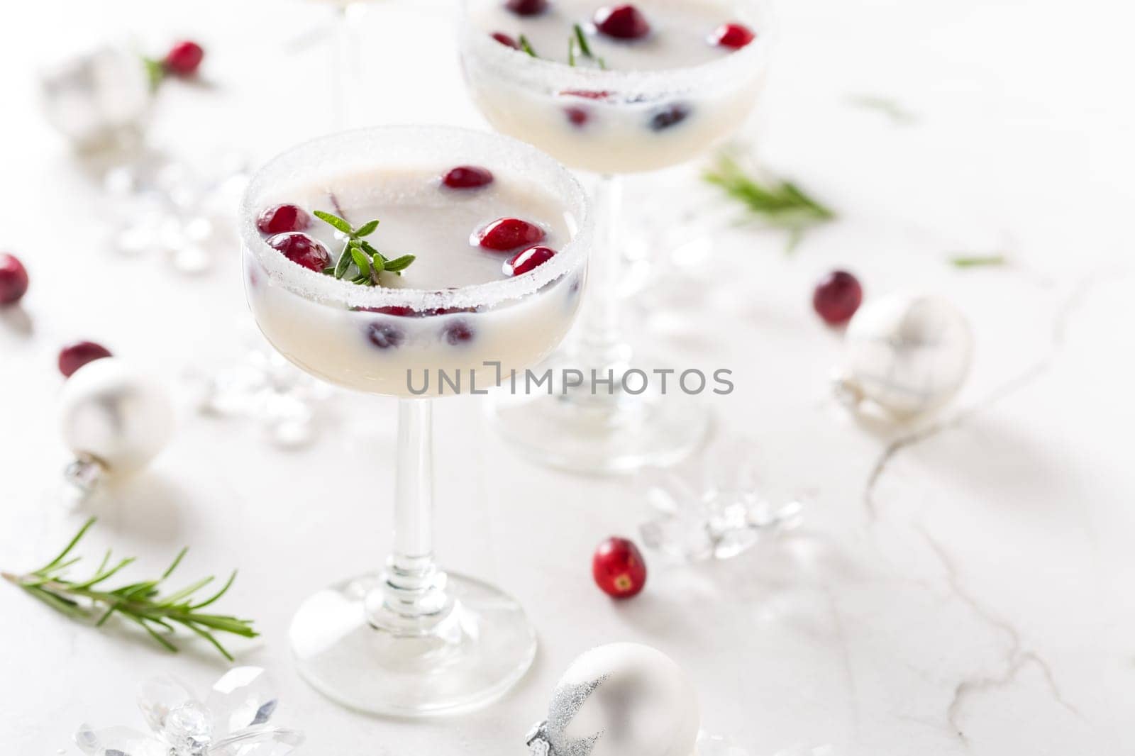 White Christmas margarita punch with cranberries and rosemary on marble background