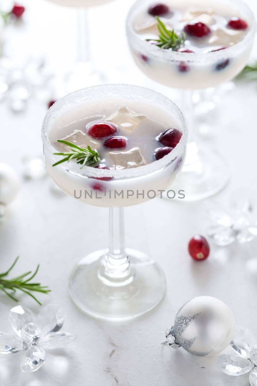 White Christmas margarita punch with cranberries and rosemary on marble background