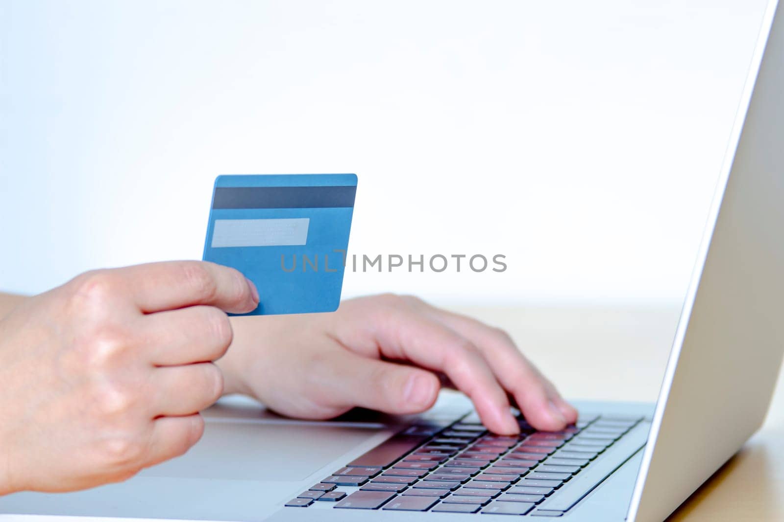A Person online shopping with a credit card and a laptop.