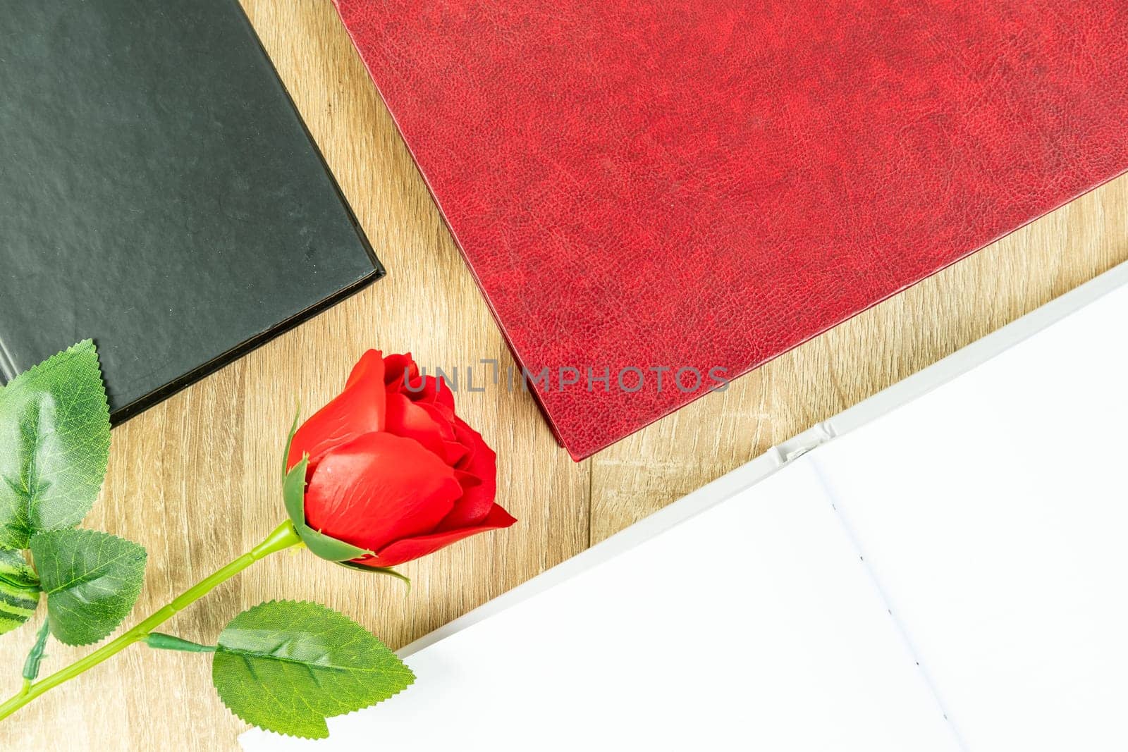 Top view shot of red roses and empty blank notebook diary and eye glasses with hardcover book on wood table,Valentine concept