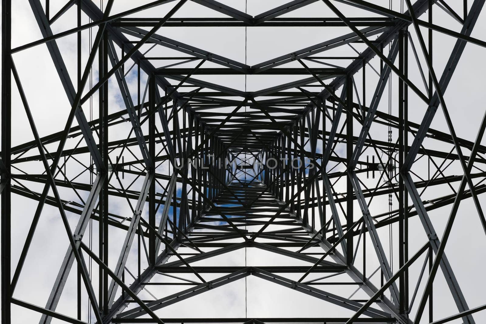 Dark abstract image of the inside of an electrical pylon. Interior skyward view, looking up, lattice structure creates an industrial themed pattern.
