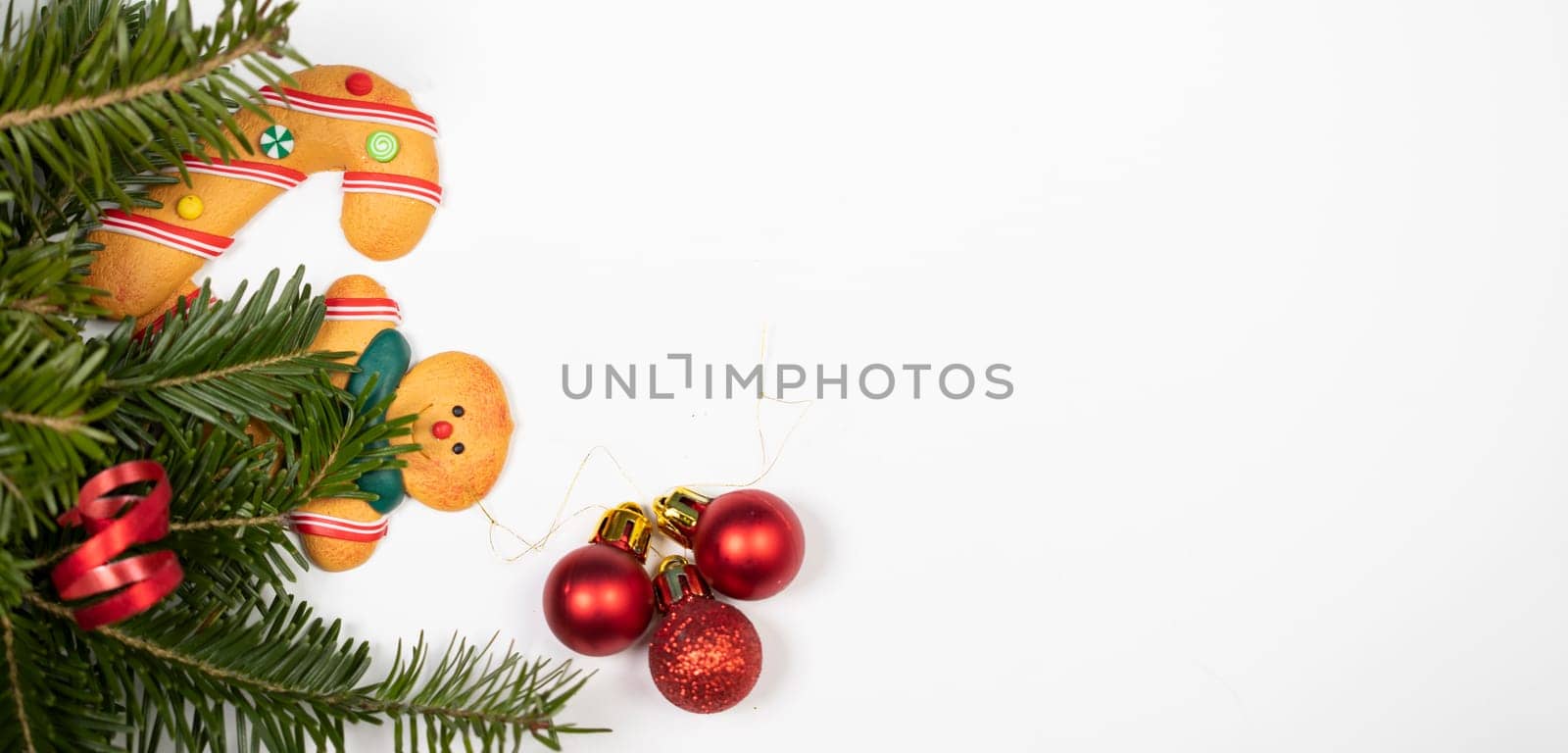 Christmas background with gingerbread cookies and pine tree branch on white.