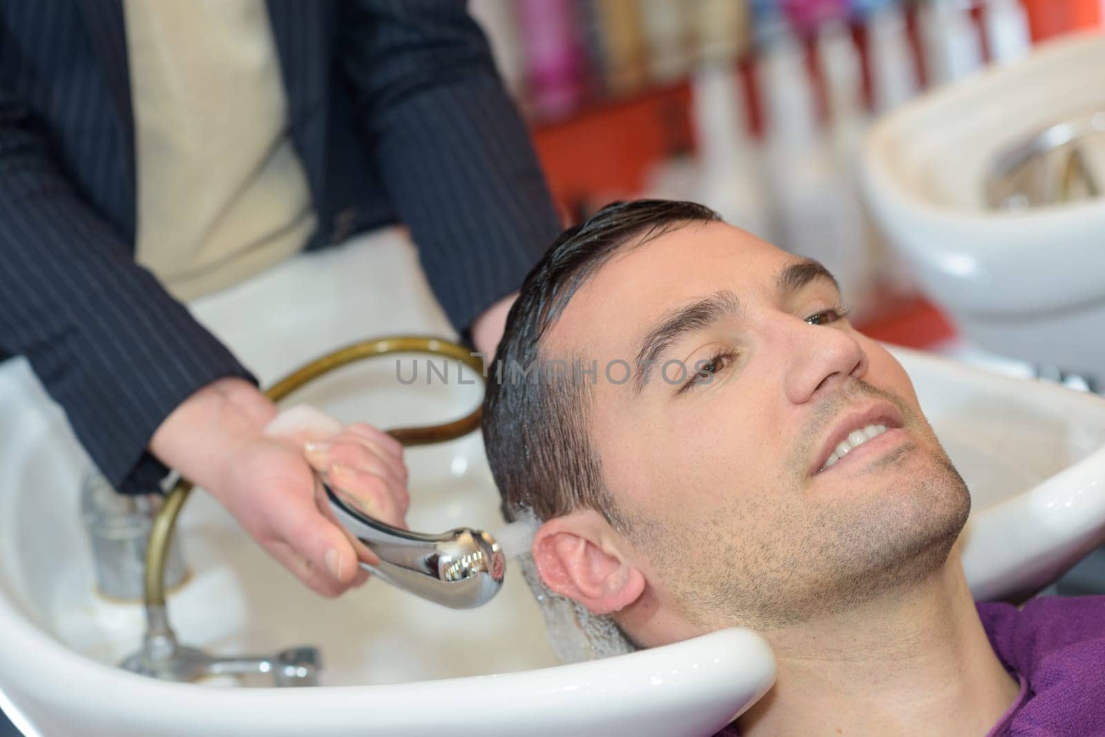 female hairdresser washing handsome clients hair