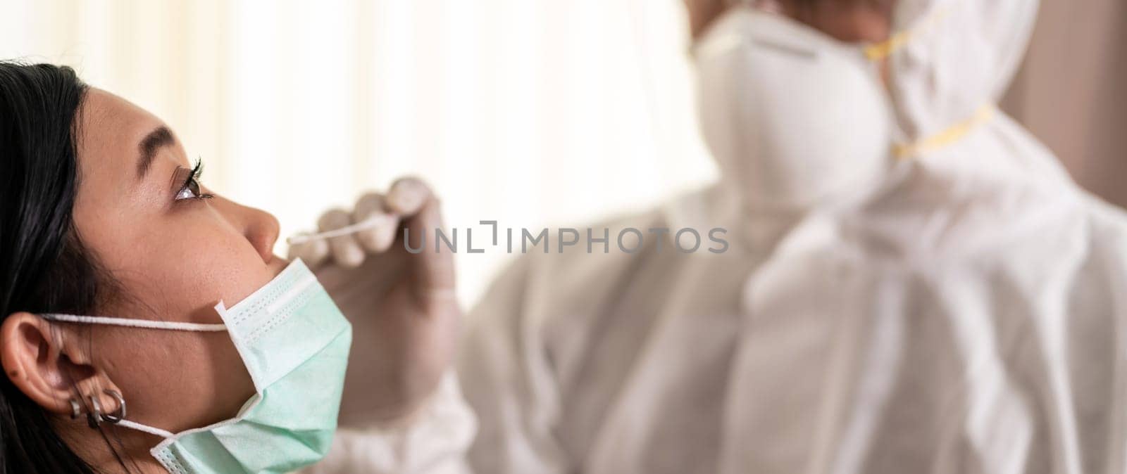 Panorama Medical staff with PPE suit test coronavirus covid-19 to asian woman by nose swab at hosputal. COVID-19 testing health care concept.