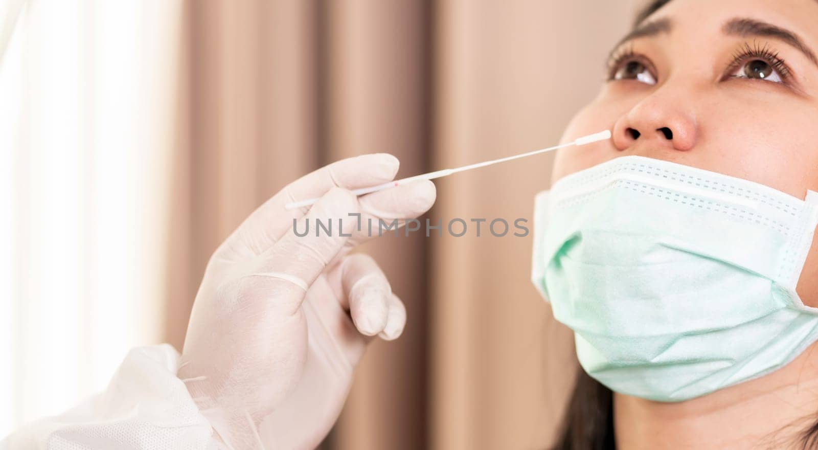 Panorama close up Medical staff with PPE suit test coronavirus covid-19 to asian woman by nose swab at hosputal. COVID-19 testing health care concept.