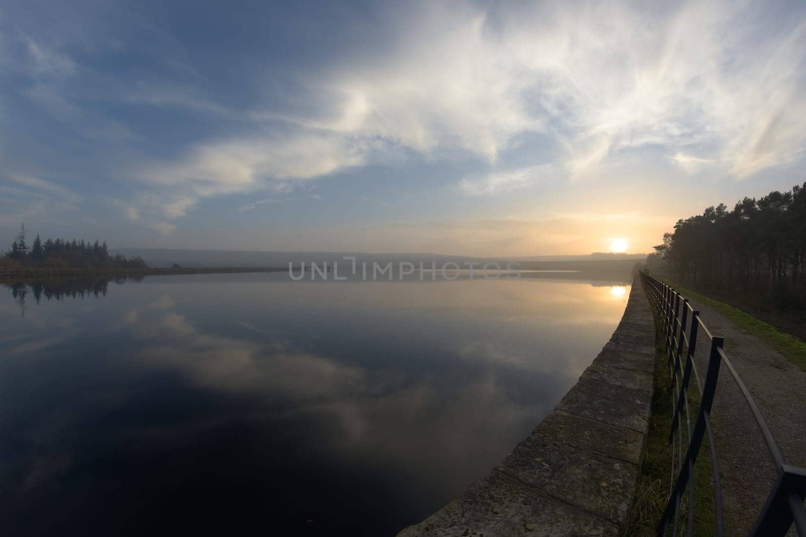 Sunset and clouds reflected in the water of redmires reservoir near sheffield. Level horizon, but fish eye distortion elsewhere. Expansive cloudscape
