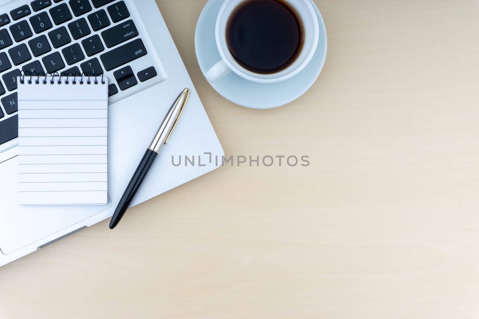 Laptop, notepad, fountain pen and cup of coffee on wooden background. Business and copy space concept..