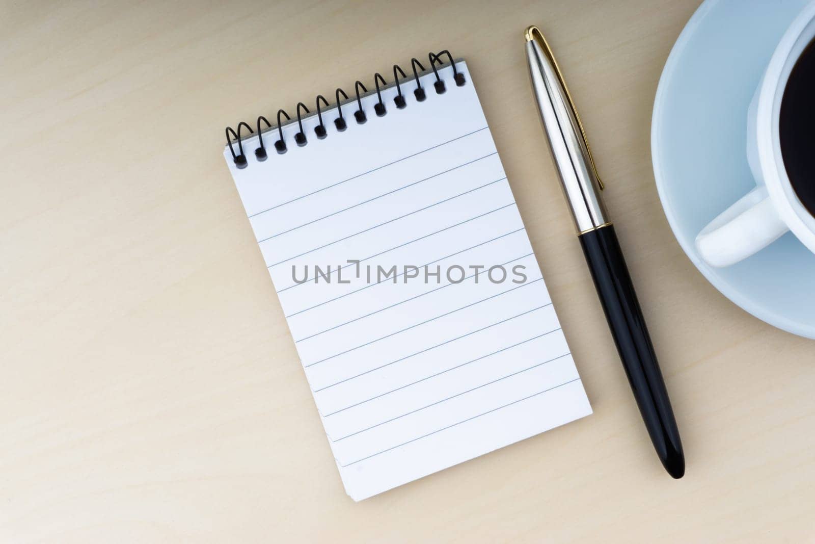 Fountain pen, notepad and cup of coffee on wooden background. Business and copy space concept..