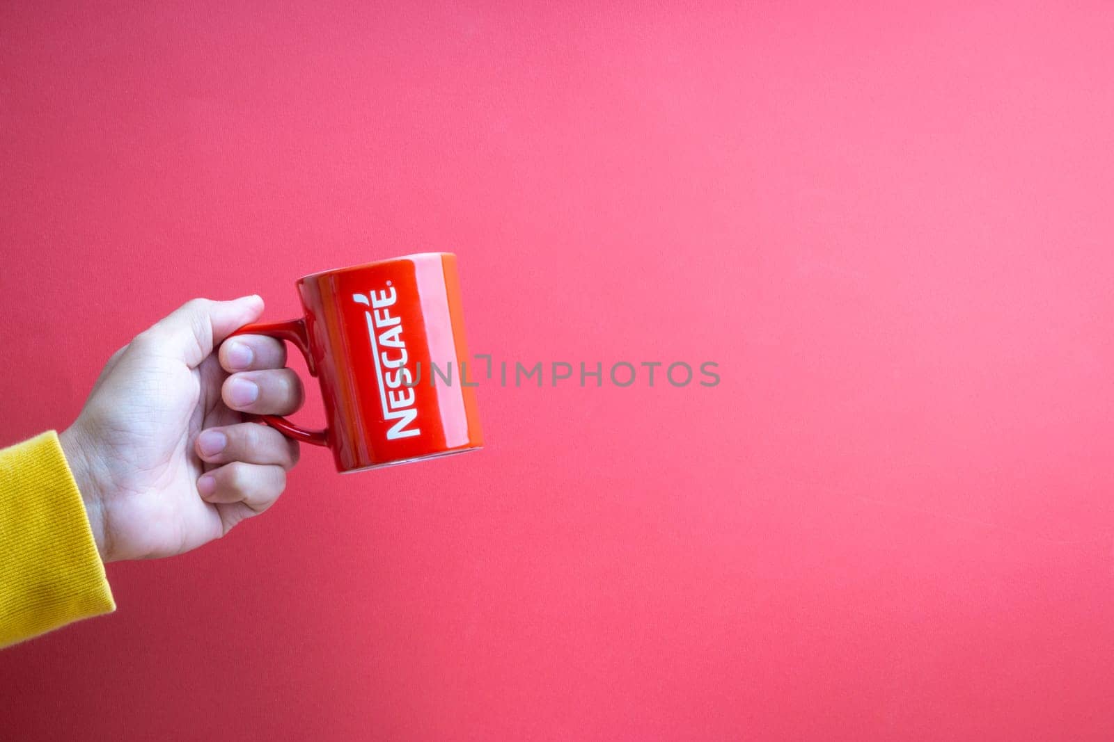 Kuala Lumpur, Malaysia - November 12, 2020 : Hand holding Nescafe Mug on red background