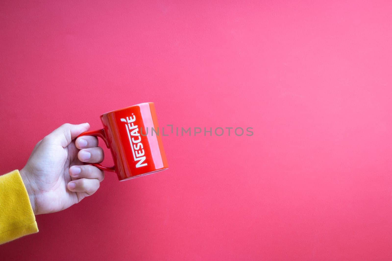 Kuala Lumpur, Malaysia - November 12, 2020 : Hand holding Nescafe Mug on red background
