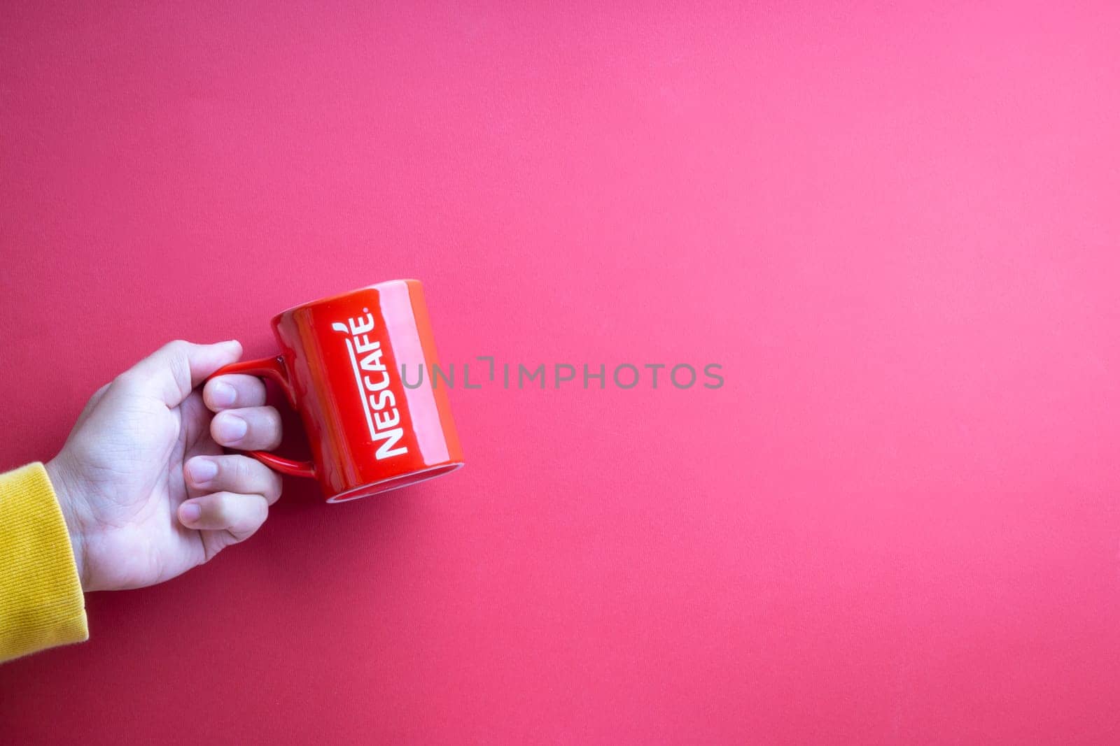 Kuala Lumpur, Malaysia - November 12, 2020 : Hand holding Nescafe Mug on red background