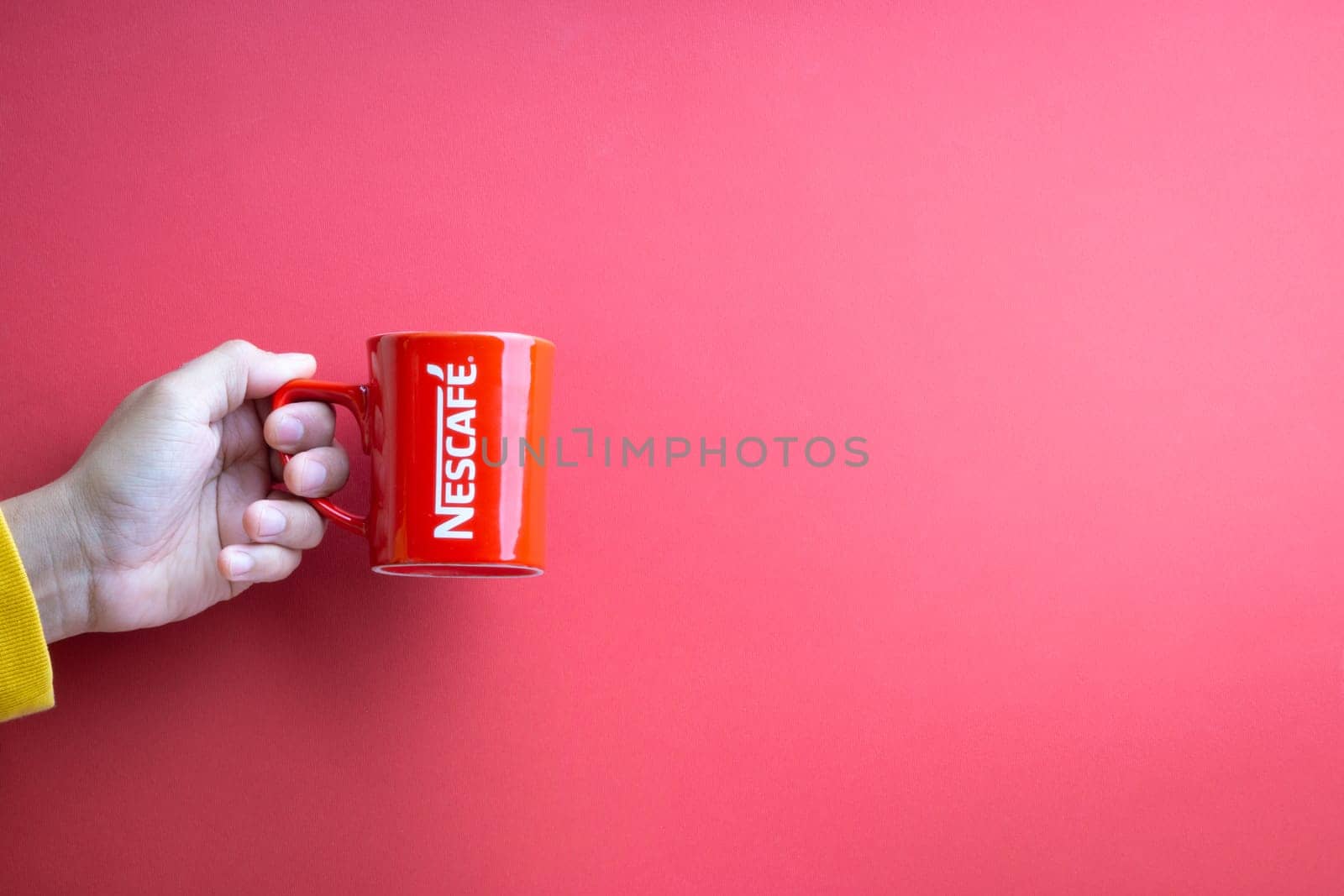 Kuala Lumpur, Malaysia - November 12, 2020 : Hand holding Nescafe Mug on red background