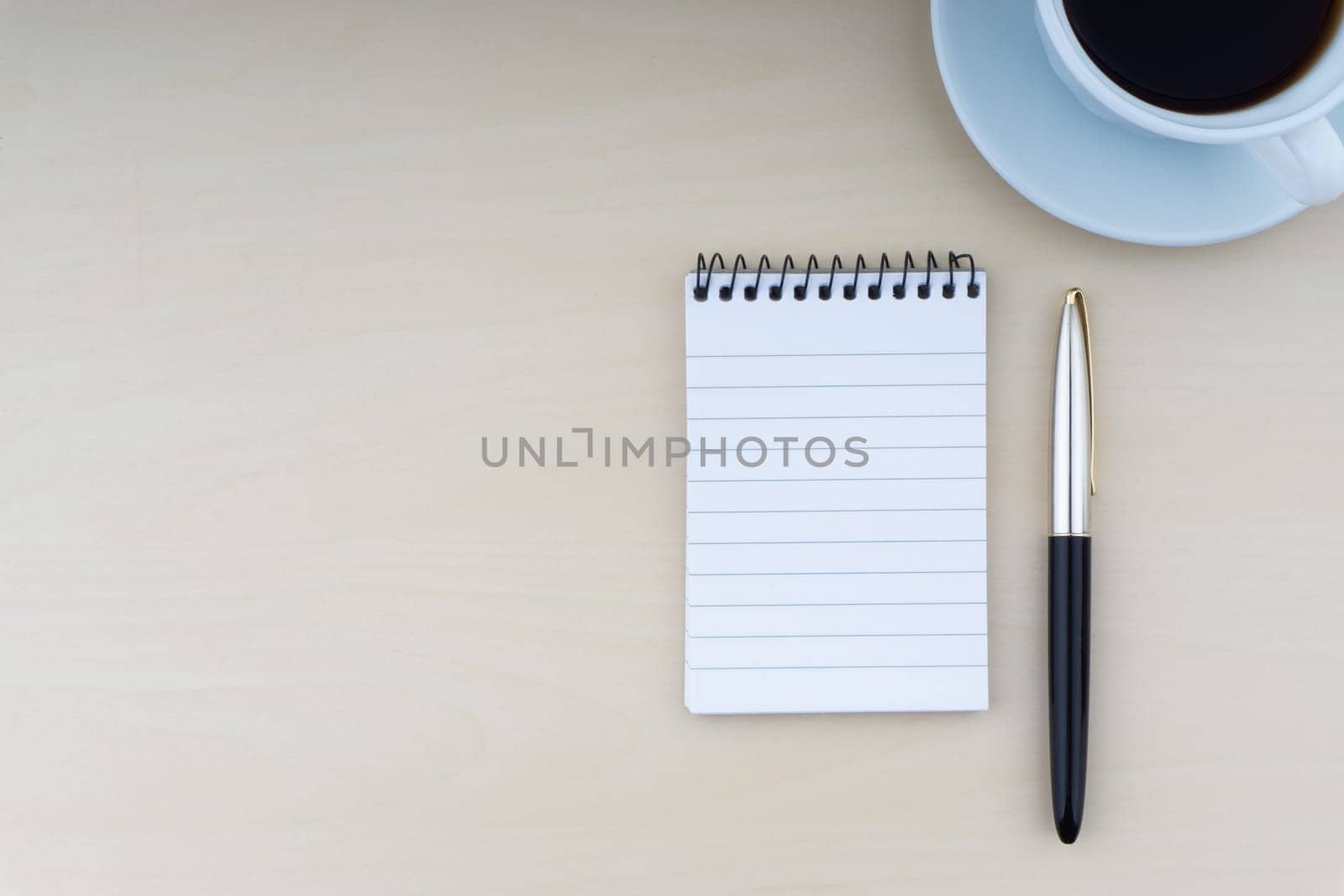 Fountain pen, notepad and cup of coffee on wooden background. Business and copy space concept..