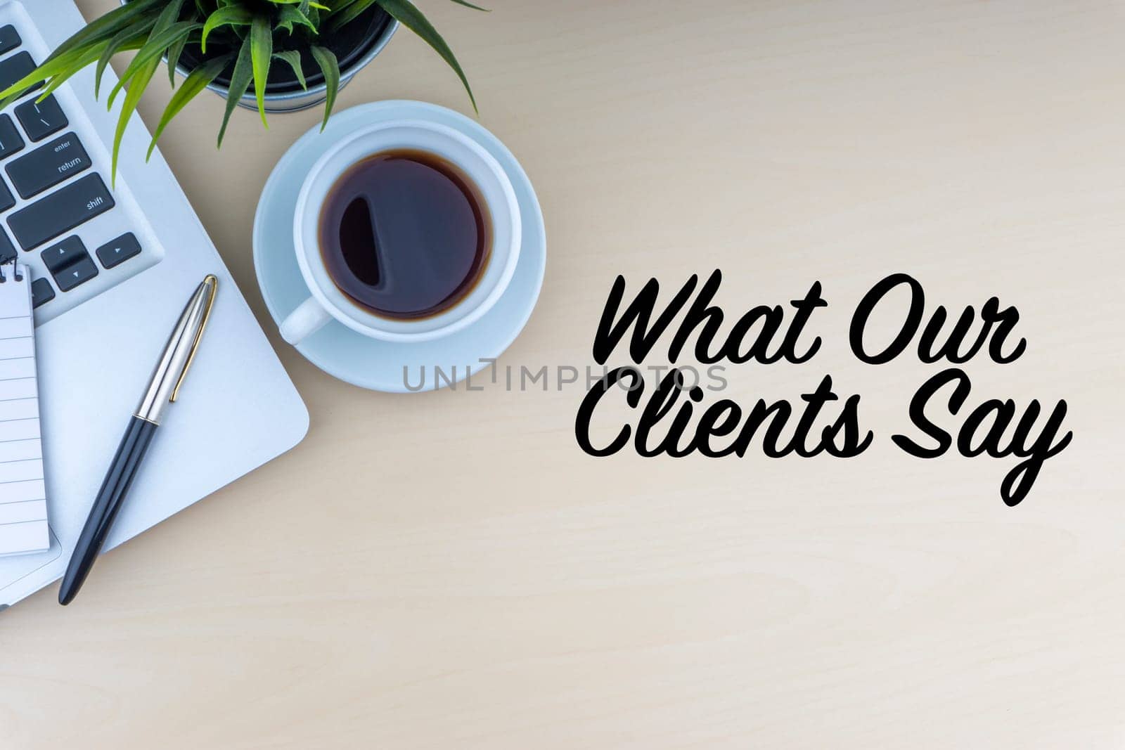 WHAT OUR CLIENTS SAY text with fountain pen, laptop, notepad, decorative flower and cup of coffee on wooden background. Business and copy space concept..