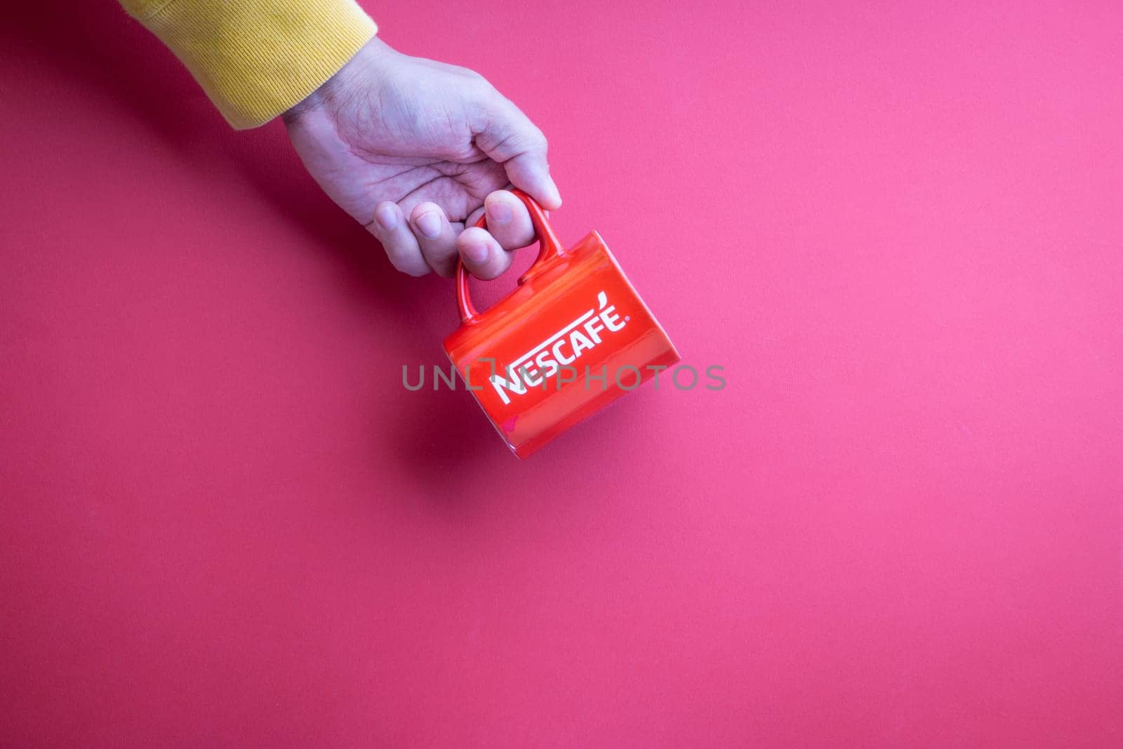 Kuala Lumpur, Malaysia - November 12, 2020 : Hand holding Nescafe Mug on red background