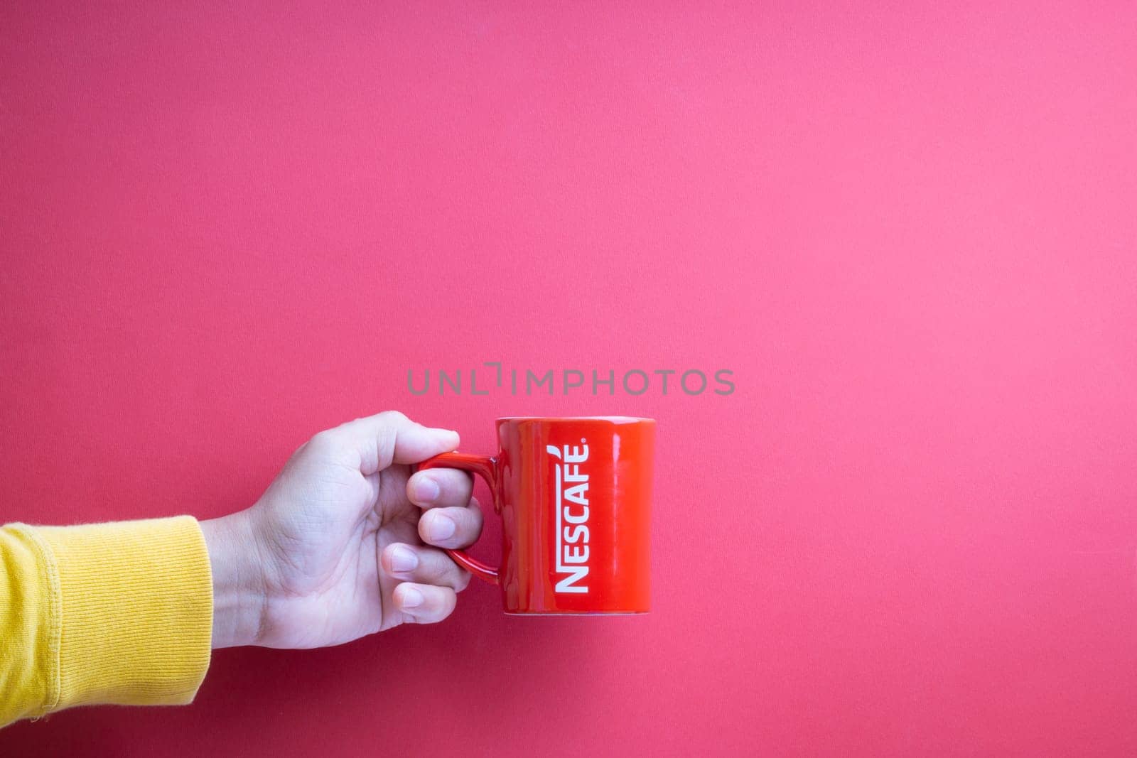 Kuala Lumpur, Malaysia - November 12, 2020 : Hand holding Nescafe Mug on red background