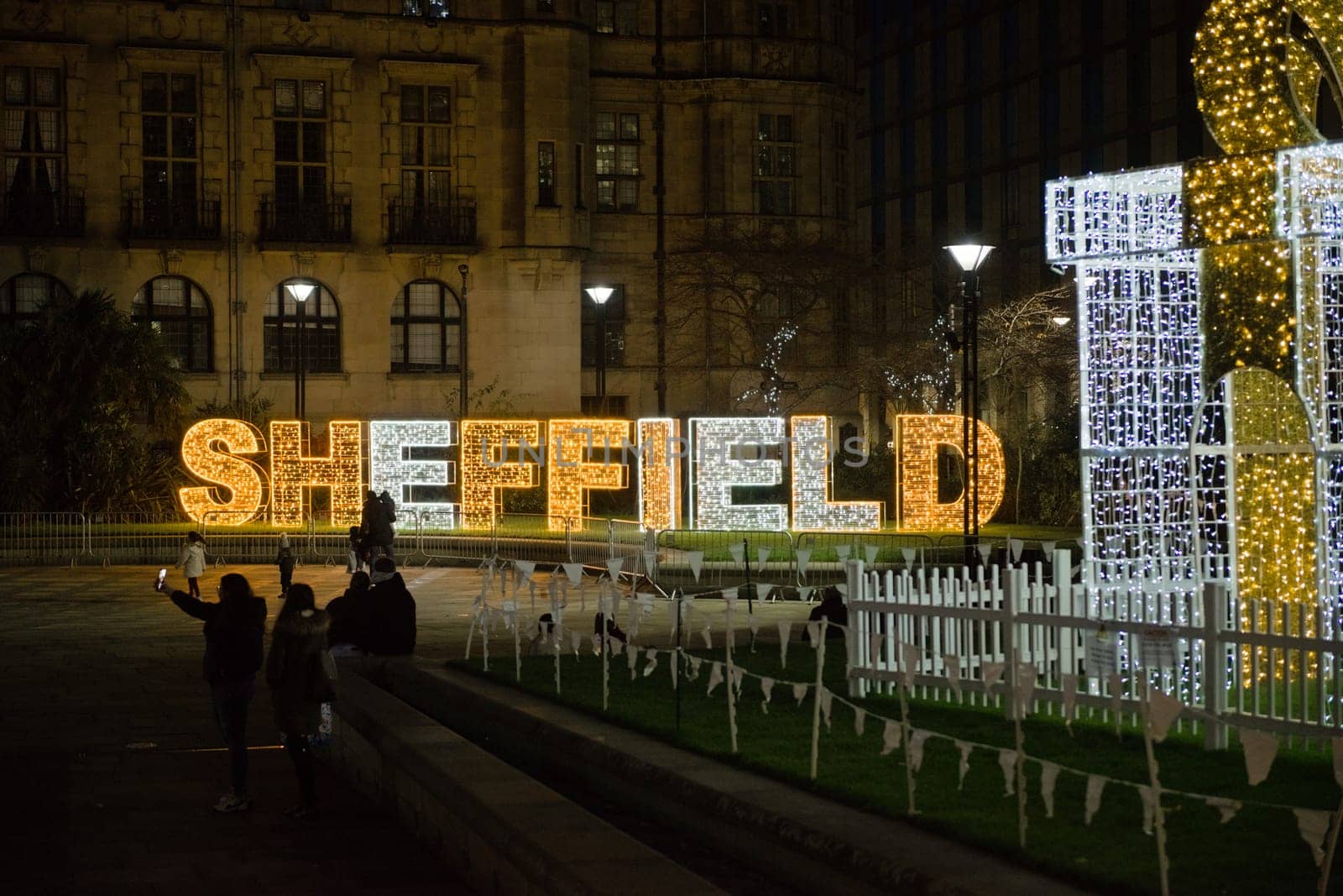 Sheffield, United Kingdom, 27th November, 2020: City center christmas light display in the peace gardens area. People taking photos with the lit gift