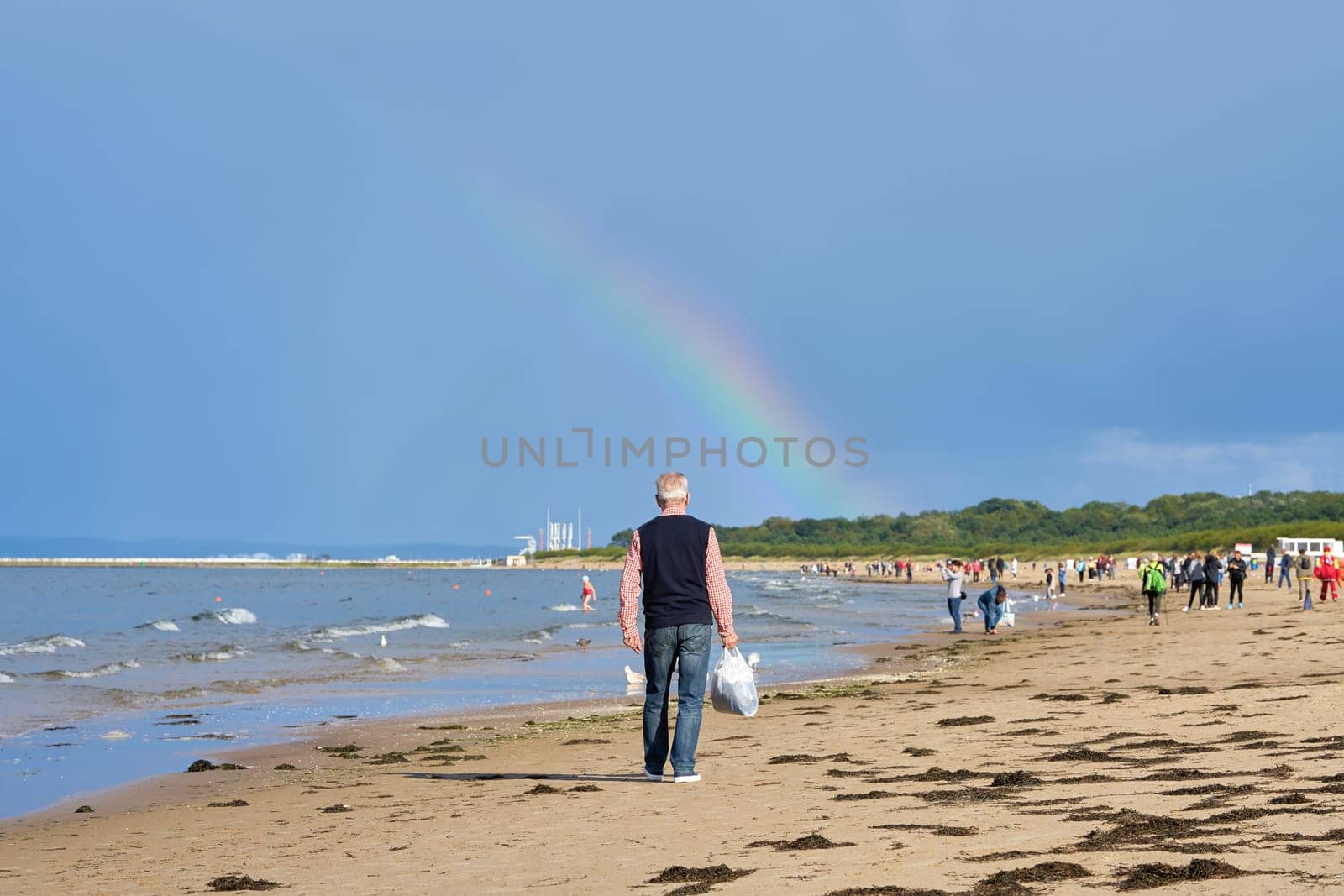 Holidaymakers on the beach of Swinoujscie on the Baltic Sea. In the background a rainbow.