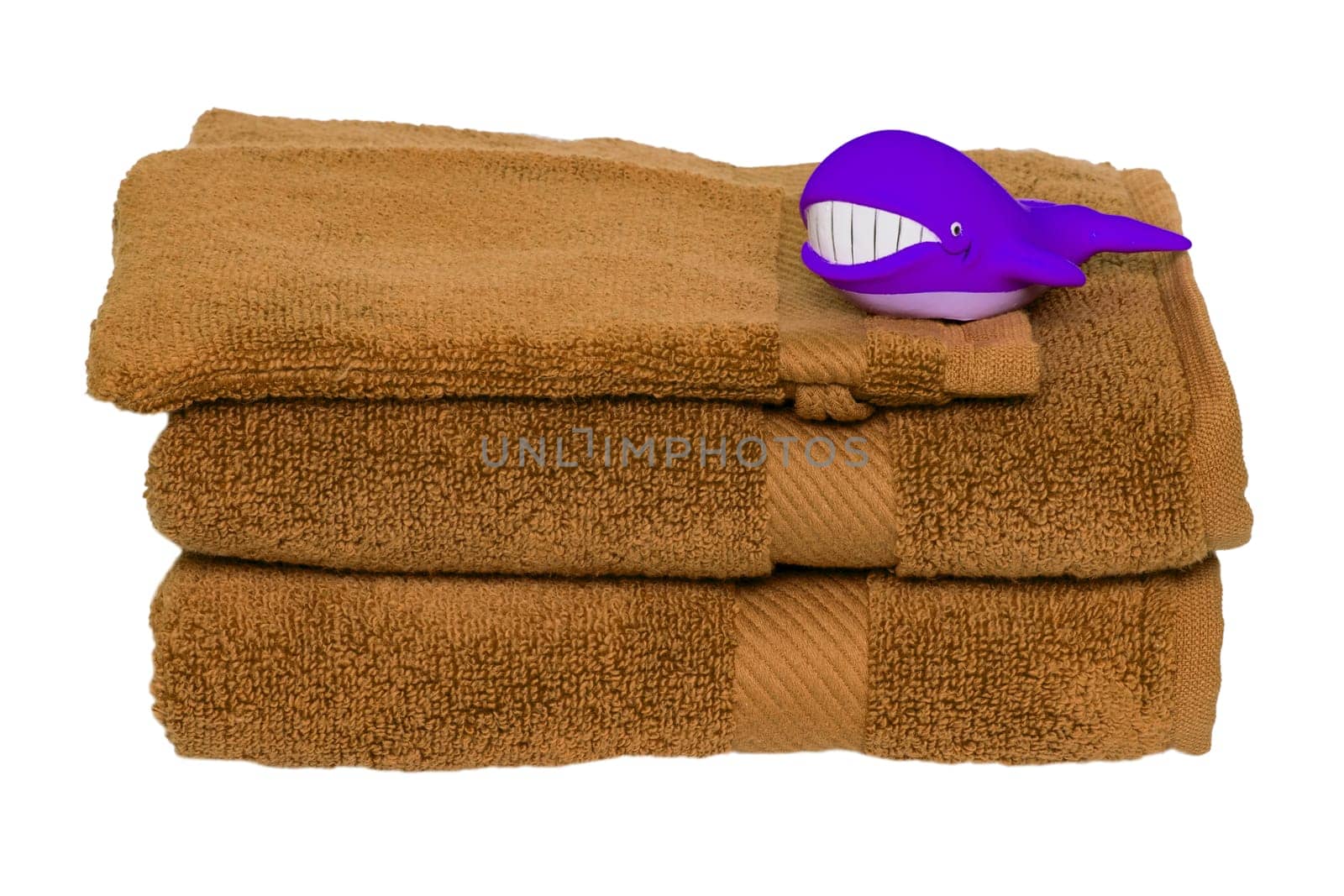 Brown towels isolated. Closeup of a stack or pile of brown soft terry bath towels with funny whale on it isolated on a white background.