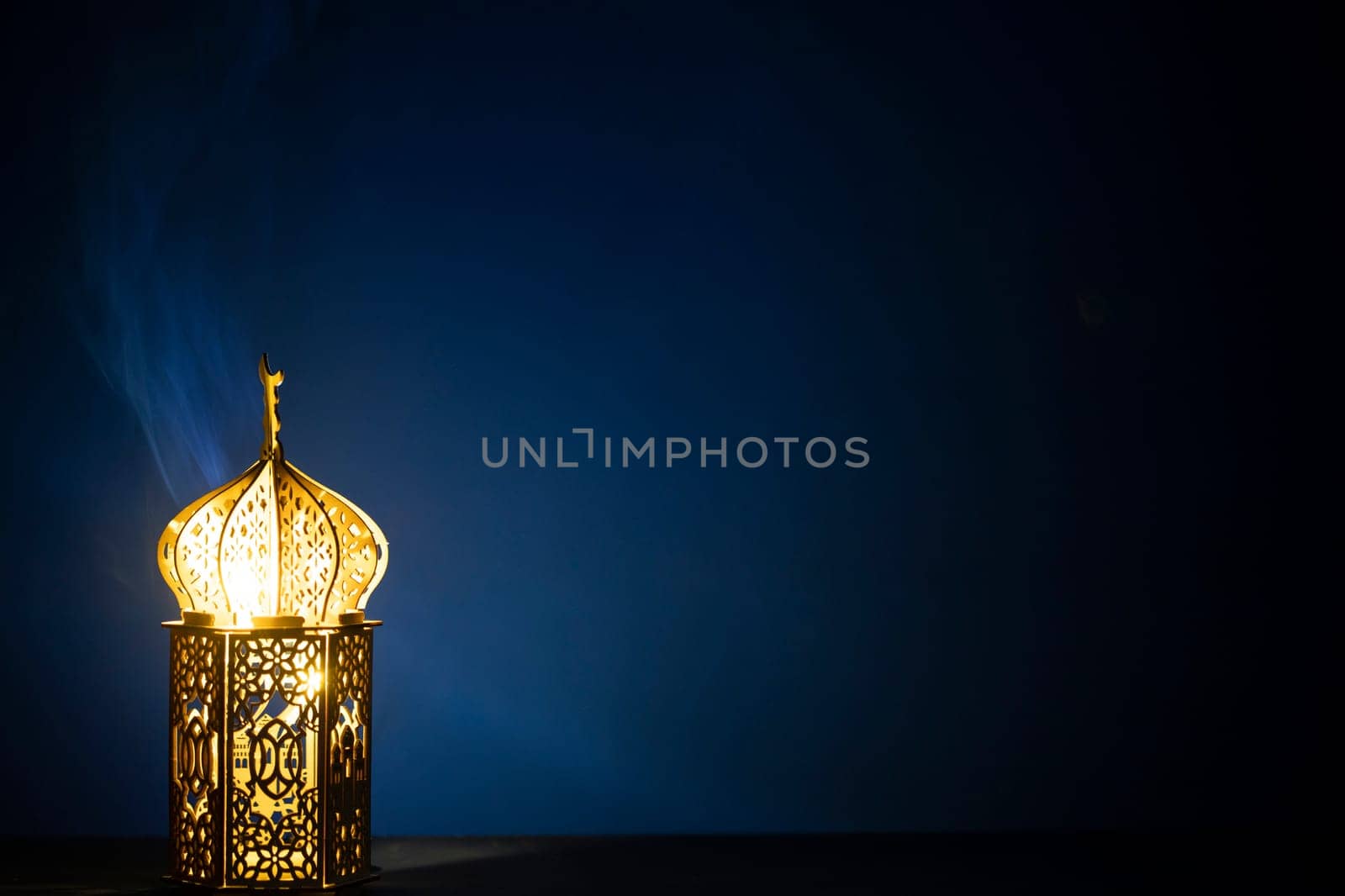 Ornamental Arabic lantern with burning candle glowing at night and glittering golden bokeh lights. Festive greeting card for Muslim holy month Ramadan Kareem.