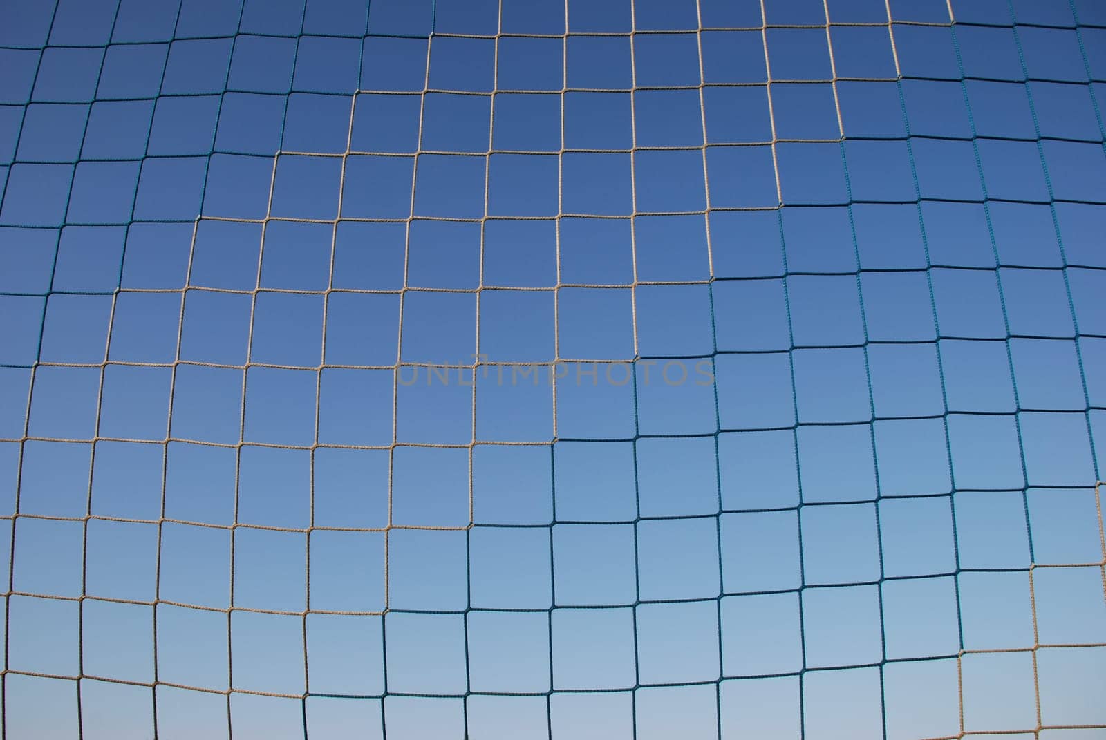A blue and white goal net for ball sports such soccer,handball and volleyball. In the background the blue sky.