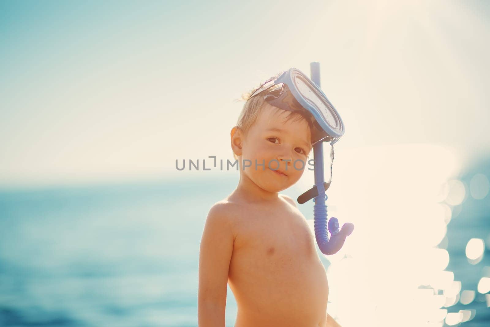 three years old boy playing at the beach with swimming mask. Child on family vacations at sea
