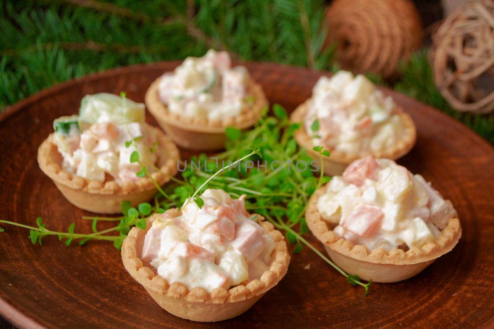 Christmas salad with vegetables in tartlets on a brown plate