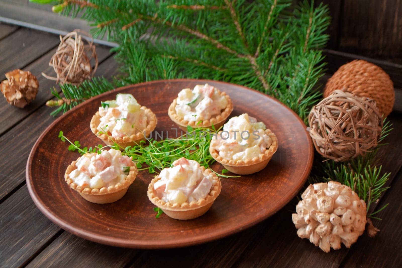big brown plate, standing on the wooden table and served with a tartlets with olivier salad and piece