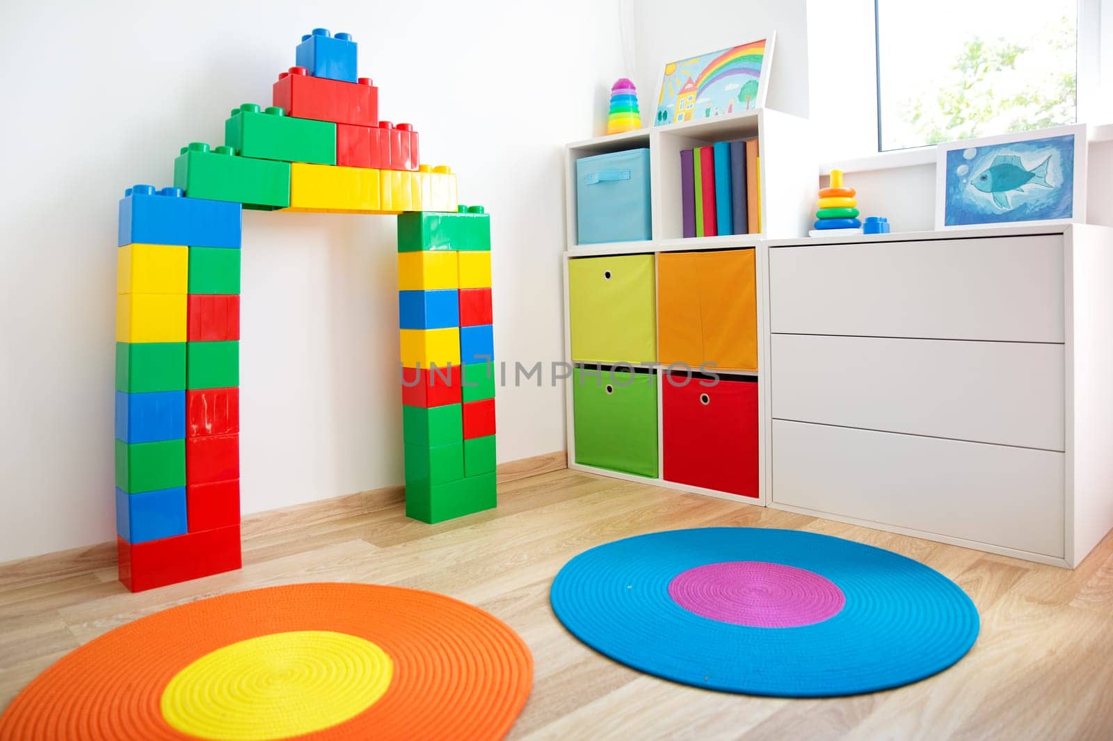 Colourful children rooom with white walls and furniture. Cunstrucktor at home interior with a window