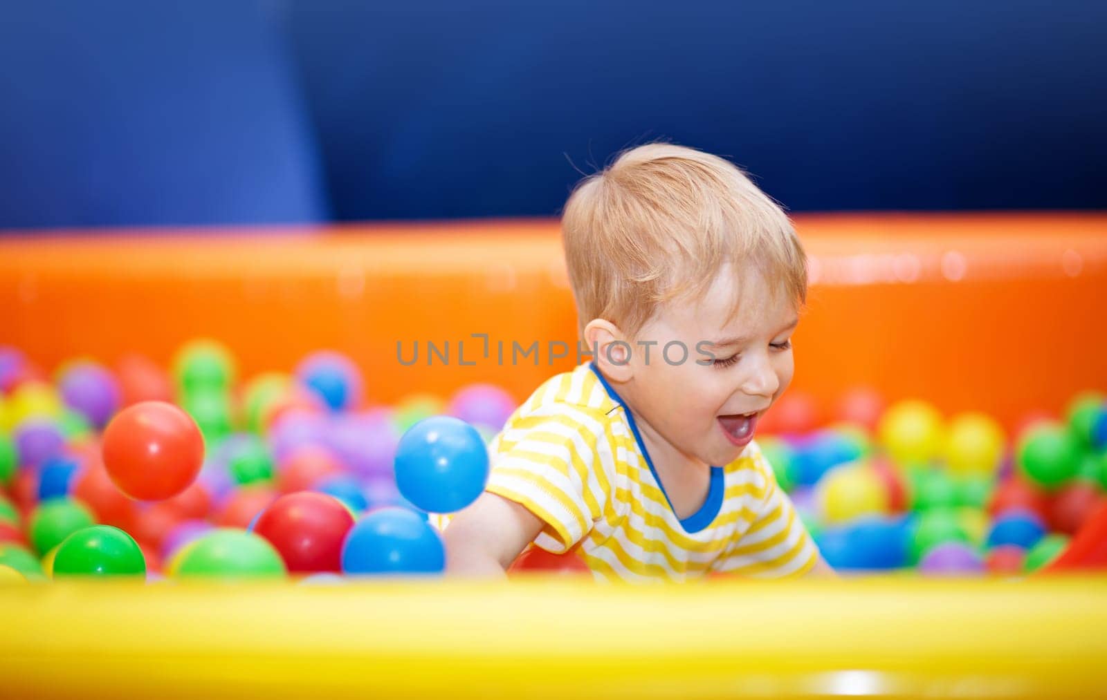 Little boy playing on playroom with ballpit and laughing