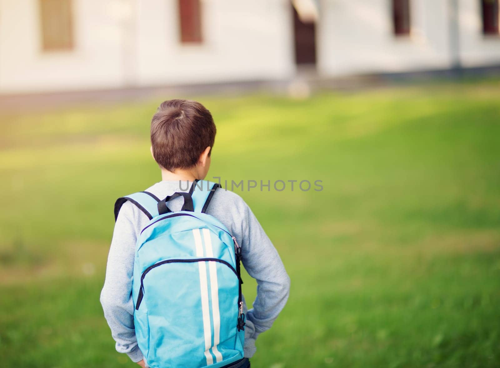 Boy with rucksack infront of a school building. Child with a backpack