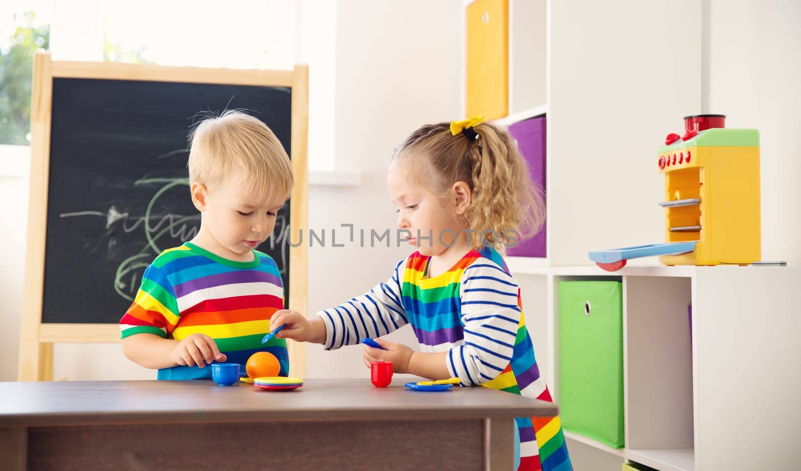 Little children playing with toys in kindergarten. Boy and girl in white room at home